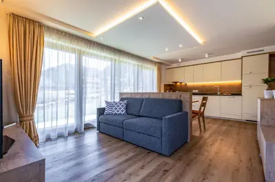 a living room with a blue couch and a kitchen at Chalet Morin in San Martino in Badia
