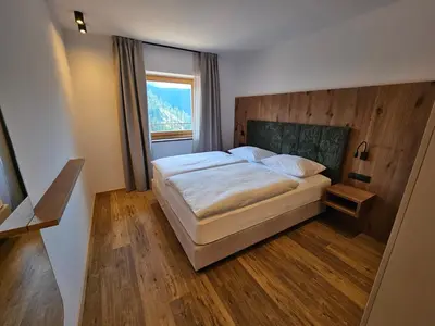 a bedroom with a bed with a wooden headboard and a window at Apartments Kranebitt in Eggen