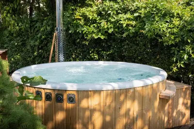 a hot tub with a shower in a garden at Piccolo Orso Bruno in Cavareno