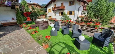 a miniature garden with chairs and flowers in a yard at Inter Hotel B&B in Vigo di Fassa