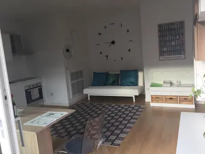 a living room with a couch and a clock on the wall at Appartamento Ligeia in Bolzano