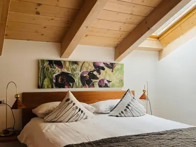 a bedroom with a large bed with white sheets and pillows at Casanemone in Tesero
