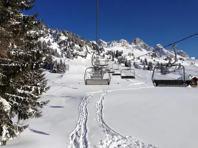 a group of huts covered in snow in front of mountains at Residence Rododendro in Passo San Pellegrino