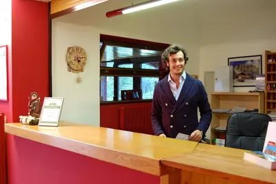 a man standing at a counter in an office at Residence Rododendro in Passo San Pellegrino