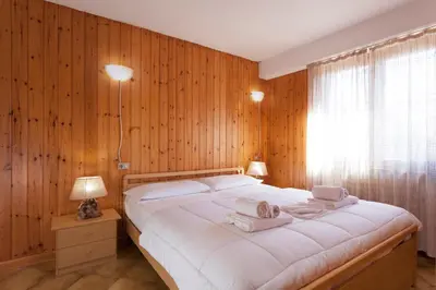 a bedroom with a large white bed with wooden walls at Residence Rododendro in Passo San Pellegrino