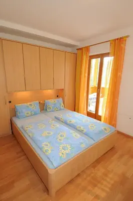 a bedroom with a bed with a blue comforter at Haus Hofer *** in Andrian