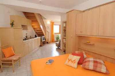 a living room with an orange couch and a kitchen at Haus Hofer *** in Andrian