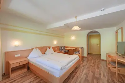 a bedroom with a bed and a desk and a television at Garni Hotel Sonnleitenhof in Caldaro