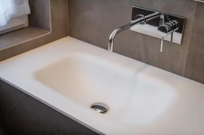 a white sink in a bathroom with a faucet at Garni Hotel Sonnleitenhof in Caldaro