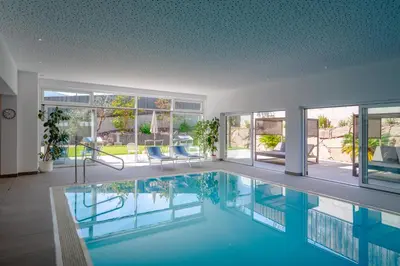 a large swimming pool in a house with windows at Garni Hotel Sonnleitenhof in Caldaro