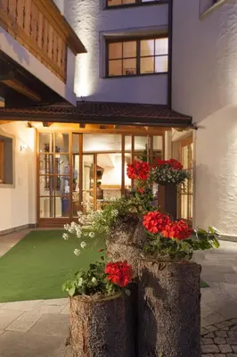 a house with red flowers in front of it at Landhotel Tharerwirt in Valdaora
