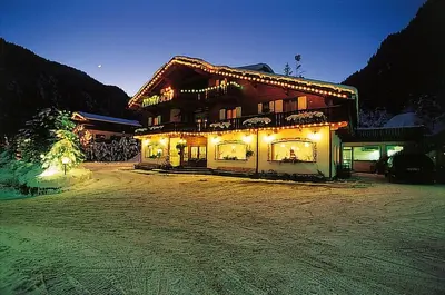 a large building with lights on it at night at Hotel Camoscio in Rocca Pietore