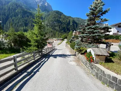 a road with a fence and a tree on a mountain at Hotel Camoscio in Rocca Pietore