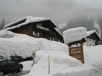 a snow covered building with a sign in front of it at Hotel Camoscio in Rocca Pietore