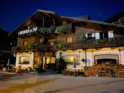 a building with tables and umbrellas in front of it at Hotel Camoscio in Rocca Pietore
