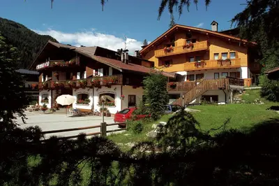 a large building with a car parked in front of it at Hotel Camoscio in Rocca Pietore