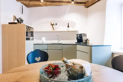 a kitchen with a table with a bowl of fruit on it at Amplatz 1523 - B&B and Suites in Montagna