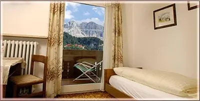 a bedroom with a window with a view of a mountain at Garni Sayonara in Selva di Val Gardena
