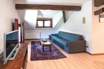 a living room with a blue couch and a table at Apartments Waldquell in Collalbo