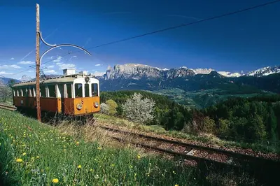 a train on the tracks with mountains in the background at Apartments Waldquell in Collalbo
