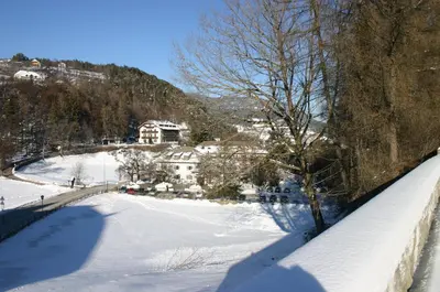 a winter view of a snow covered field next to a wall at Apartments Waldquell in Collalbo