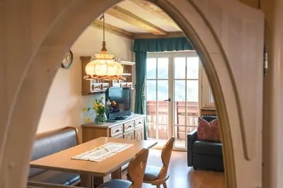a living room with a dining room table and a room with a window at Residenz am Kaiserweg in Longomoso