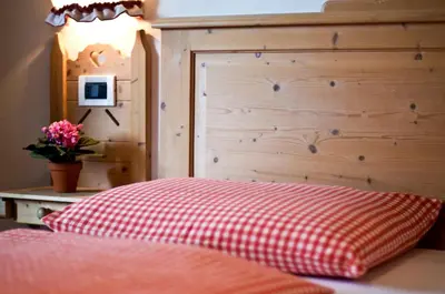a bed with a red and white checked pillow next to a wooden headboard at Residenz am Kaiserweg in Longomoso