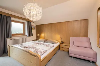 a bedroom with a large bed and a pink chair at Appartamenti Elbrus in Santa Cristina in Val Gardena