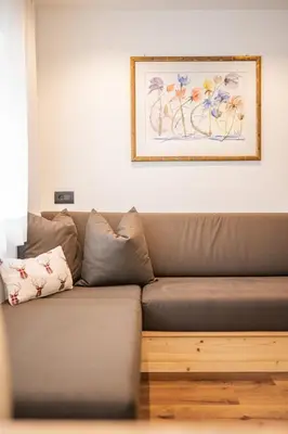 a brown couch in a living room with a picture on the wall at Appartamenti Elbrus in Santa Cristina in Val Gardena