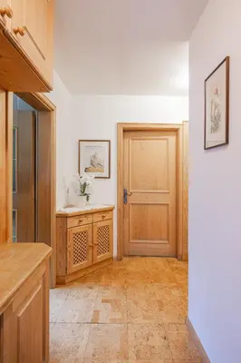 a kitchen with a wooden door and a tiled floor at Appartamenti Elbrus in Santa Cristina in Val Gardena