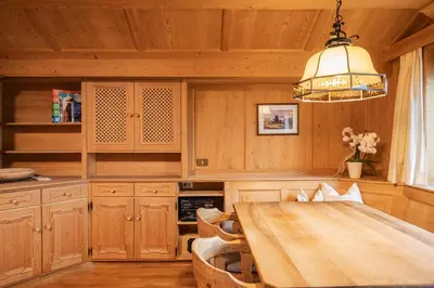 a kitchen with a wooden table and a chandelier at Appartamenti Elbrus in Santa Cristina in Val Gardena