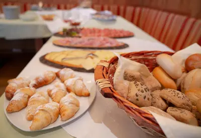 a table topped with plates of bread and a basket of pastries at Gasthaus Bad Siess in Longomoso