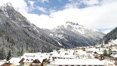 a town in the mountains with snow covered mountains at Cesa Mandi e Miky in Canazei