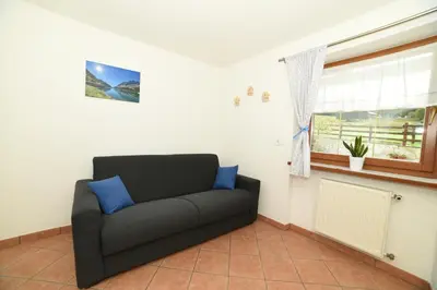a living room with a couch and a window at Cesa Mandi e Miky in Canazei