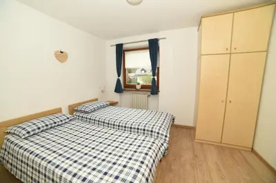 a bedroom with two beds and a window at Cesa Mandi e Miky in Canazei