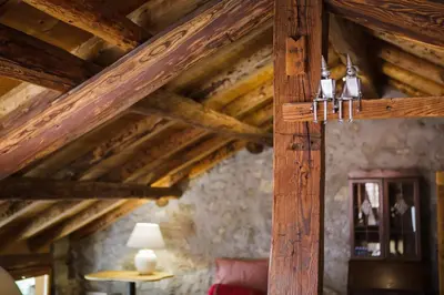 a room with wooden ceilings and a table with a lamp at LA PITA in La Valle