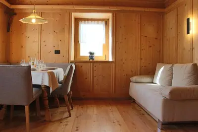 a dining room with a table and a couch at Ciasa Alfri in La Villa