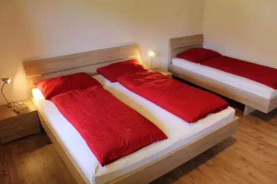 two beds in a room with red and white sheets at Volggerhof in Racines