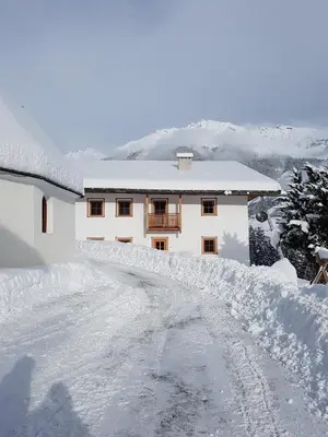 a snow covered road in front of a building at Volggerhof in Racines