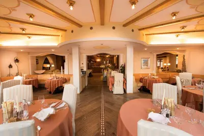 a dining room with tables and white chairs and a room with tablesktop at Hotel Patrizia Dolomites Glamour in Moena