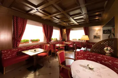 a restaurant with red booths and tables and windows at Hotel Patrizia Dolomites Glamour in Moena