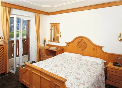 a bedroom with a bed and a mirror and a window at Hotel Patrizia Dolomites Glamour in Moena