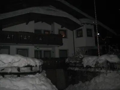 a house is covered in snow at night at B&B Ciasa Weber in Moena