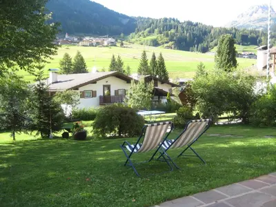 two chairs sitting in the grass in front of a house at B&B Ciasa Weber in Moena