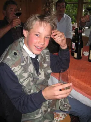 a young man sitting at a table holding a wine glass at B&B Ciasa Weber in Moena