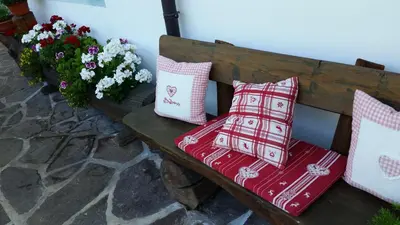 a wooden bench with pillows on it next to flowers at B&B Ciasa Weber in Moena