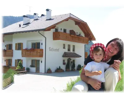 a woman and a child in front of a house at Nature Residence Telfnerhof in Laion