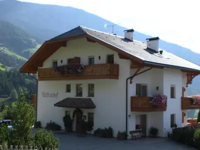 a large white building with a balcony and mountains in the background at Nature Residence Telfnerhof in Laion