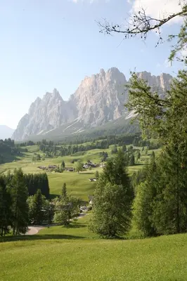 a green field with a mountain in the background at Boutique Hotel Villa Blu Cortina D'Ampezzo in Cortina dʼAmpezzo