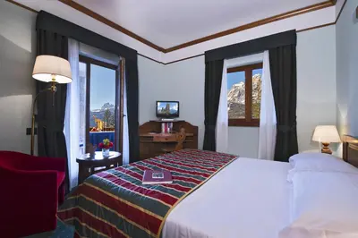a hotel room with a bed and a window at Boutique Hotel Villa Blu Cortina D'Ampezzo in Cortina dʼAmpezzo